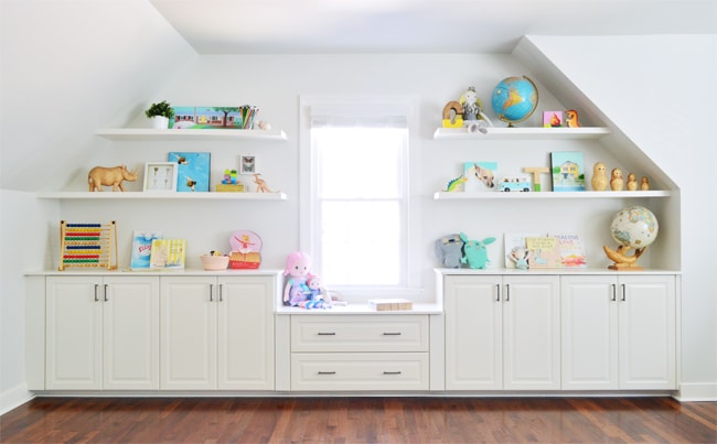 Colorful built-ins filled with toys and games, made from white cabinets and white floating shelves perfect for a kids room, playroom, or bonus room.