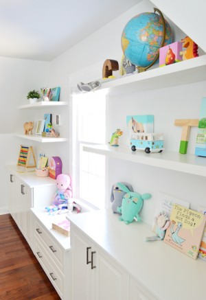White floating shelves under sloped ceiling filled with toys books and kids objects in a playroom