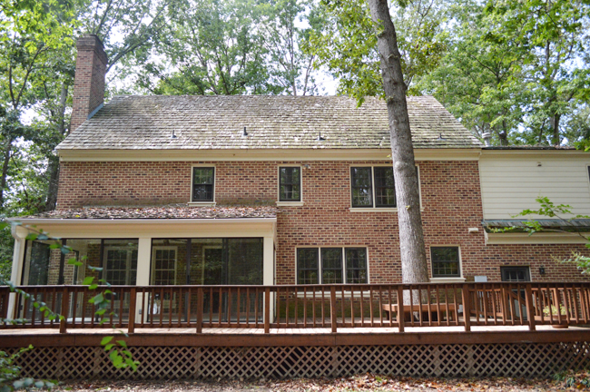 Before View Of Back Of Brick Colonial House With Large Deck