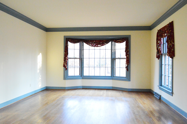 Before Photo of Living Room With Blue Trim And Dated Window Treatments