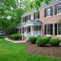 Traditional Colonial Brick House With Large Mulch Beds And Boxwood Bushes