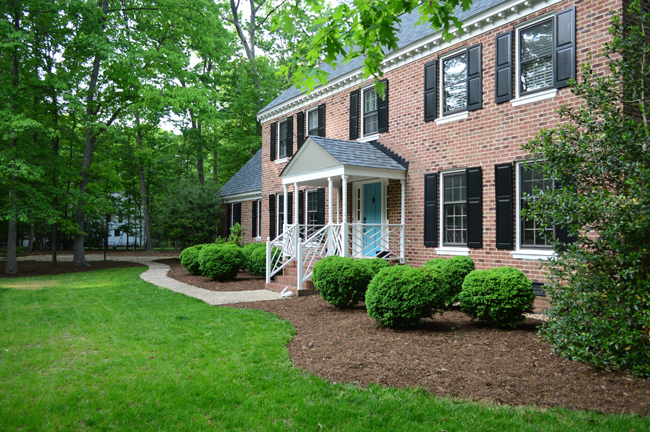 Traditional Colonial Brick House With Large Mulch Beds And Boxwood Bushes