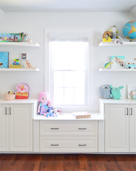 Window seat created in bonus room with built-in Ikea cabinets and white floating shelves