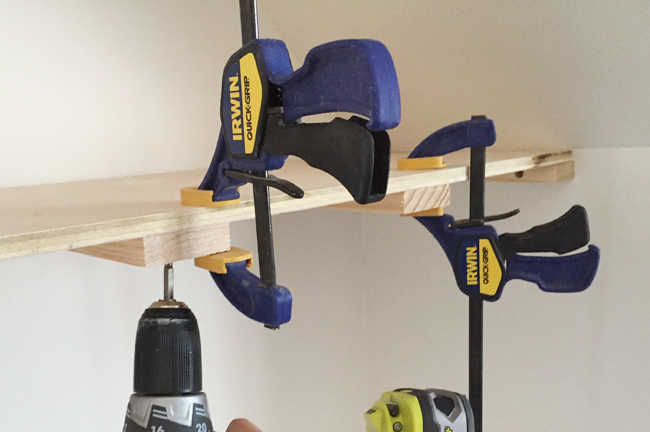 Screwing on a top plywood piece for thin floating shelves using Irwin Quick Grip clamps to hold the in place