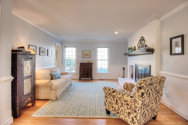 living room staged to sell with neutral walls white fireplace and minimal furniture