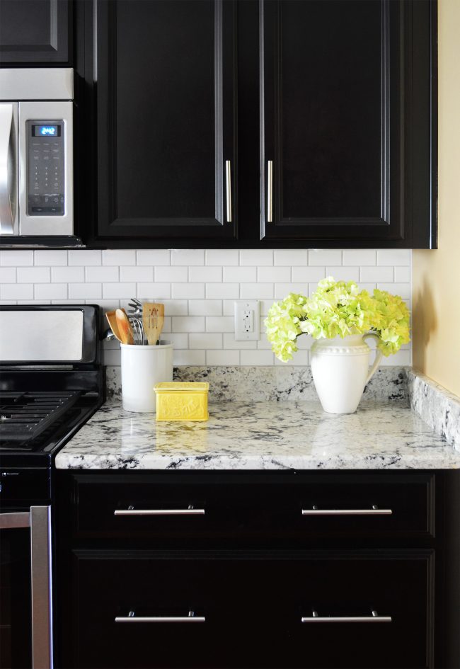 white subway tile backsplash with black cabinets