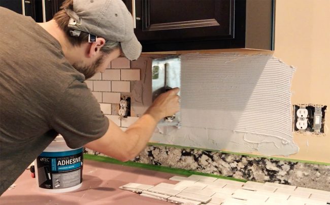 John scraping mastic with v-notch trowel on backsplash wall