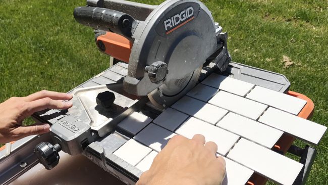 Ridgid wet saw cutting a sheet of small white subway tiles