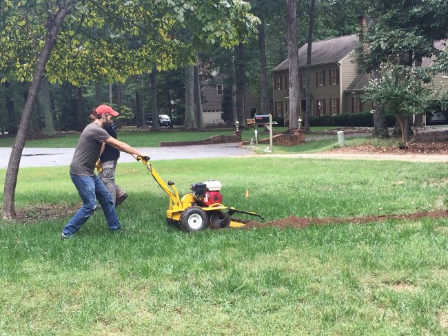 using trencher tool to dig irrigation system in front yard