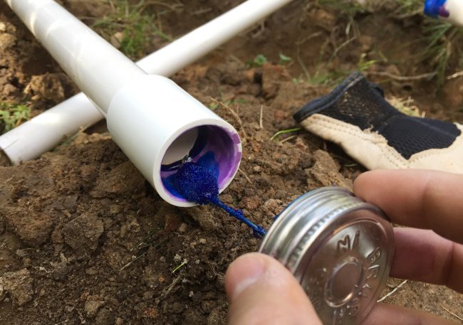 applying blue cement to inside of pvc coupling