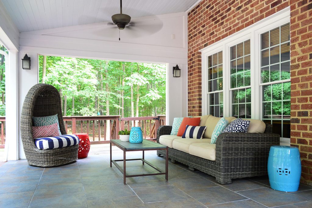 Covered sunroom patio with stained deck gate in background