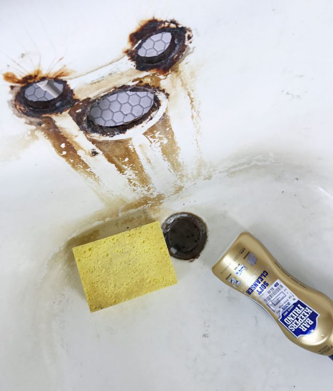 Sponge and bar keepers friend cleanser in rust stained clawfoot tub