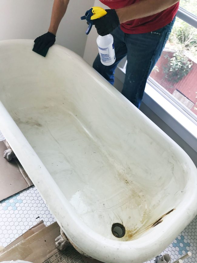 Cleaning clawfoot tub with sponge and vinegar