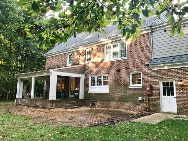 progress photo of brick house with deck removed and trim painted white
