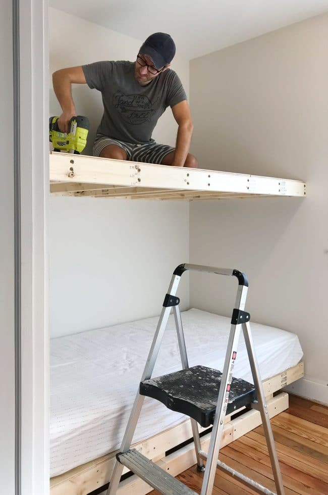 John sitting on top bunk to nail plywood into floating platform