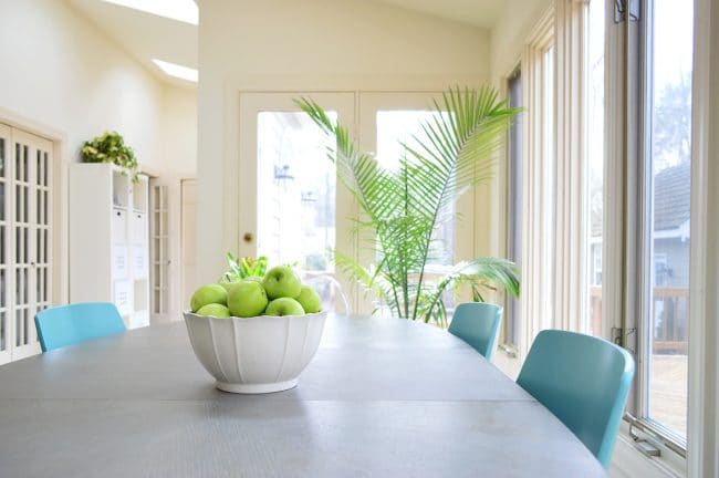 kitchen table staged to sell with simple fruit bowl and green plants