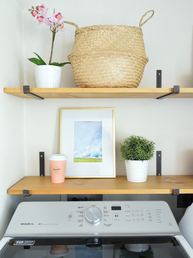 detail of open shelves above top loading washing machine with art basket orchid