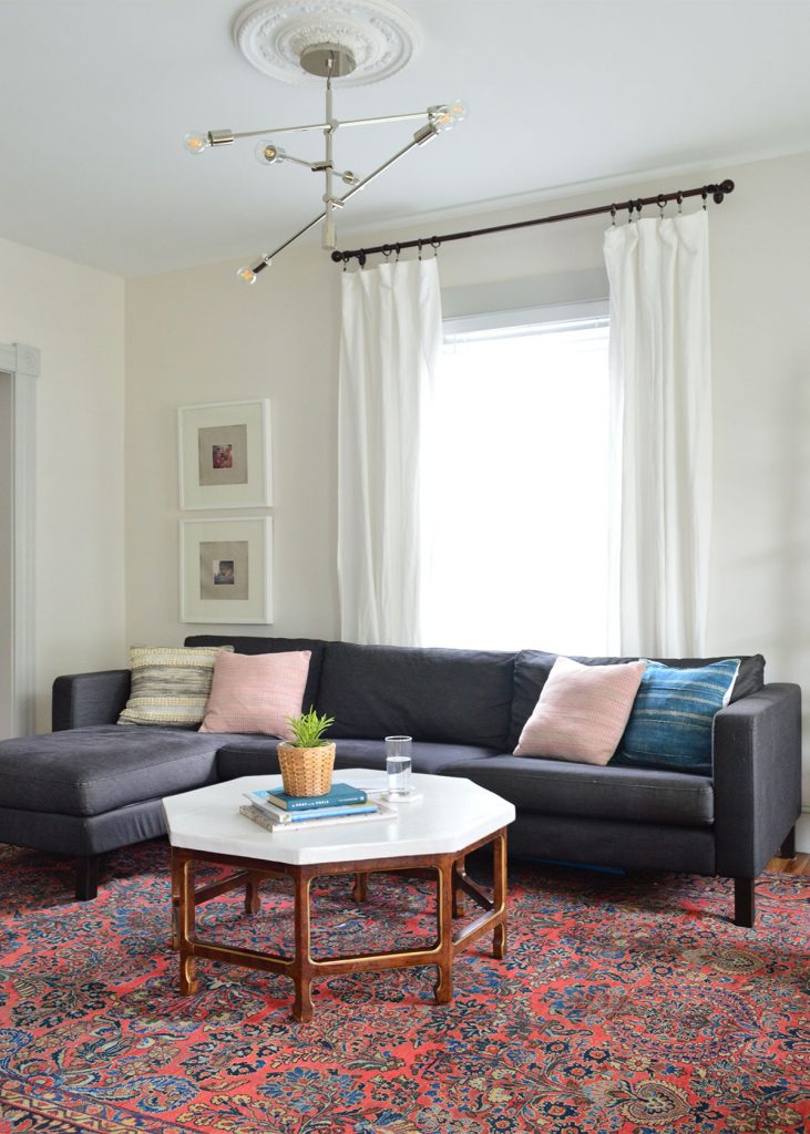 gray wall living room with red color vintage rug and dark navy ikea sectional