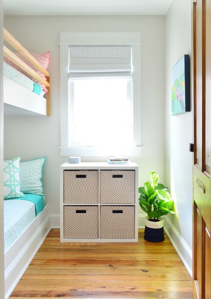 view into small room bunk beds with cubby organizer baskets under window