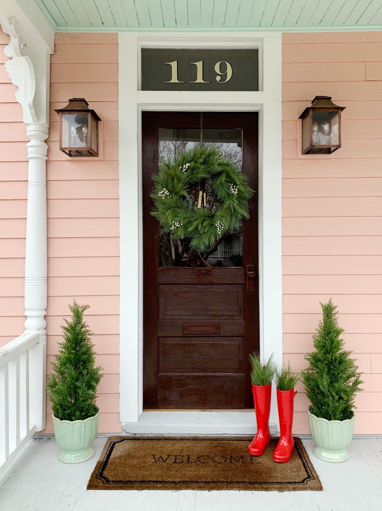 Pink House With Wood Door And Faux Christmas Wreath and Faux Trees On Both Sides