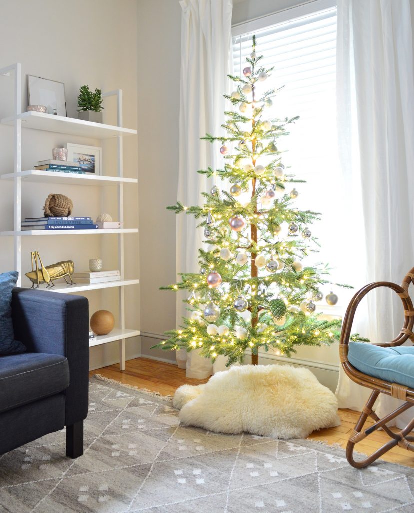 Sparse Faux Fir Prelit Christmas Tree Next To Modern Bookshelf