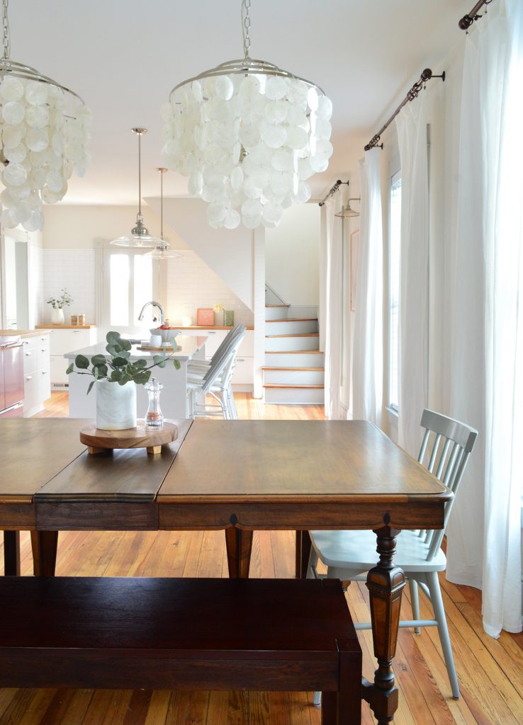 Row of curtains hung in beach house dining room using dark bronze curtain rods.