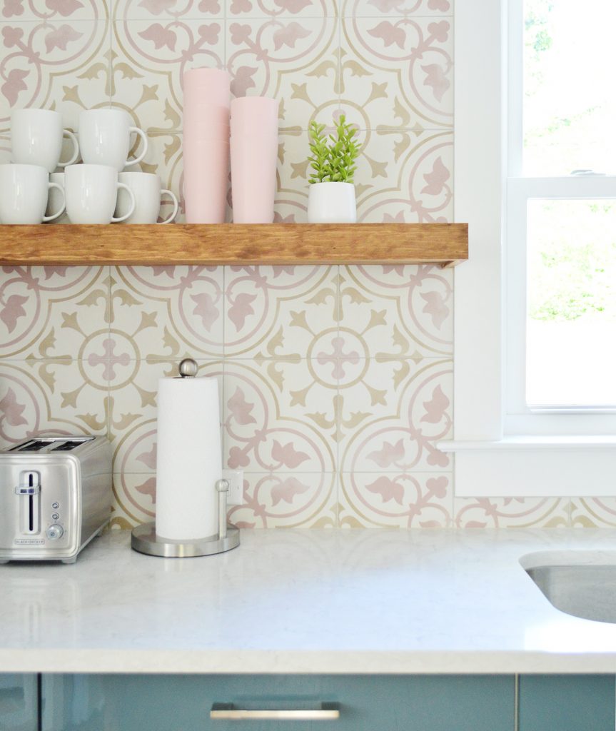 Wood Toned Floating Kitchen Shelf Against Pink Patterned Tile Backsplash