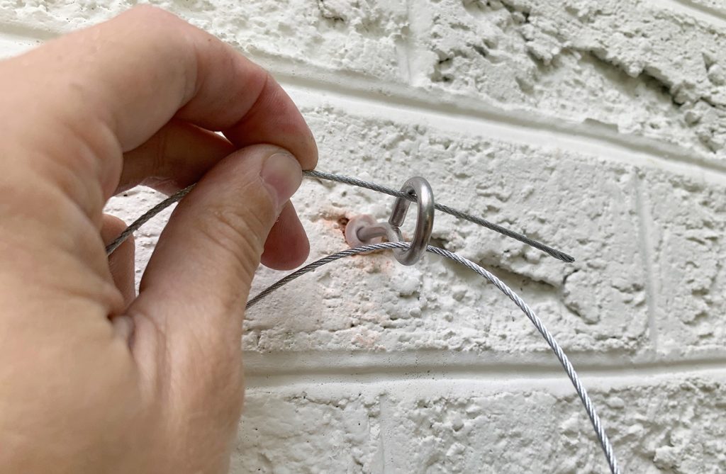 Close up of threading galvanized wire through eye hook