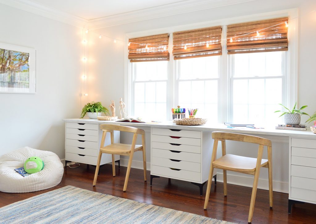 Kids Art Room With Two Wood Chairs Along Long Art Desk Workspace With String Lights