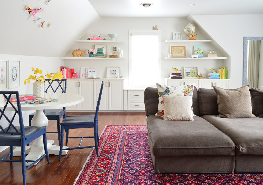 Family bonus play room with traditional rug and oversized couch and built in shelves