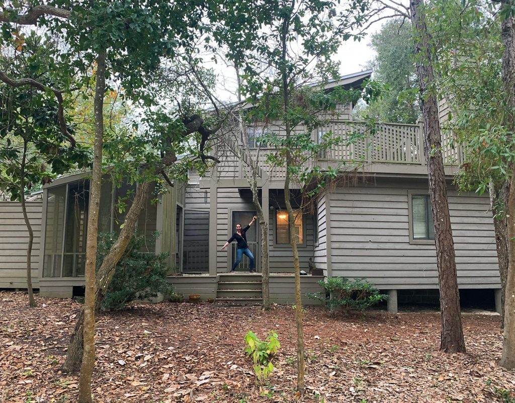 Before photo of home with brown siding and leaf covered dirt yard