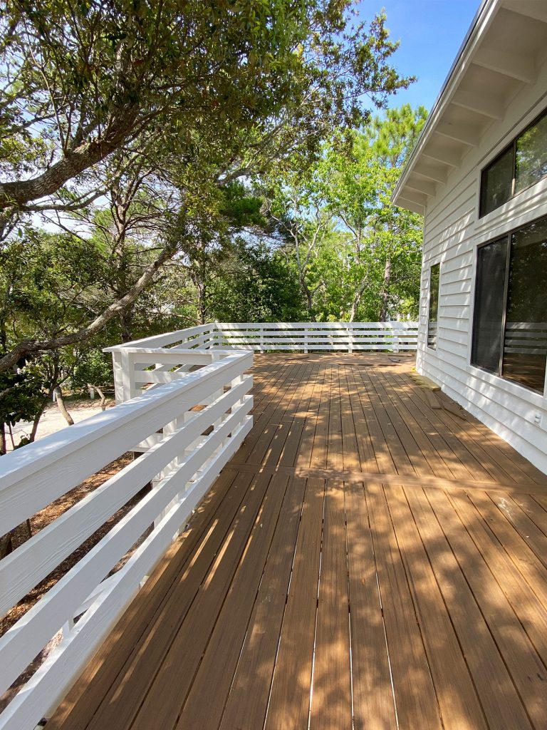 Large outside deck on white house with lots of trees