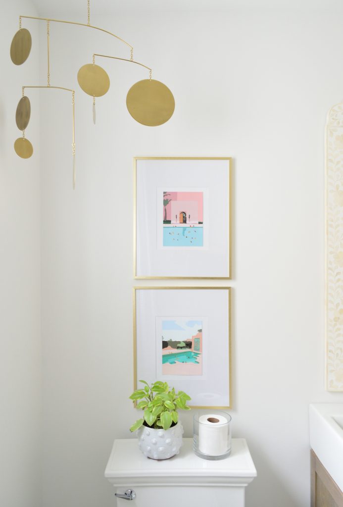 Colorful artwork in gold picture frames above toilet in bright modern bathroom