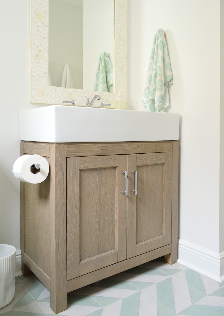 Wood vanity in modern bathroom with mint chevron tile floor