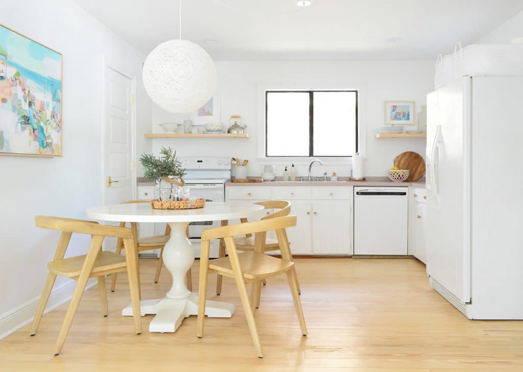 Minimal White Kitchen With White Globe Woven Chandelier over Pedestal Table