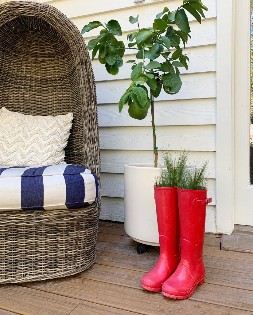 Red Rubber Boots With Faux Fir Branches Sticking Out Of them On Holiday Front Porch