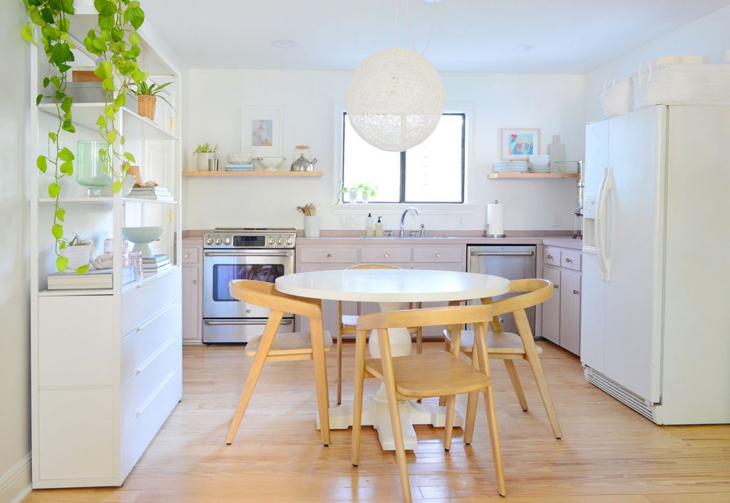 Kitchen with mauve cabinets and white metal shelf on side and round table in center