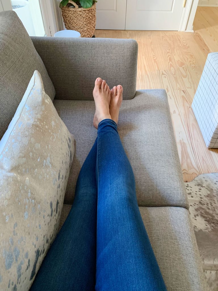 Sherry's legs stretched out on gray loveseat