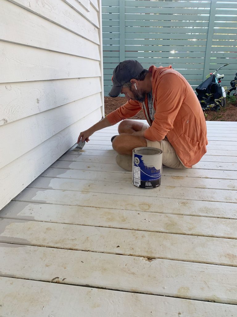 John bordeando el piso del porche con pintura gris para pisos con pincel