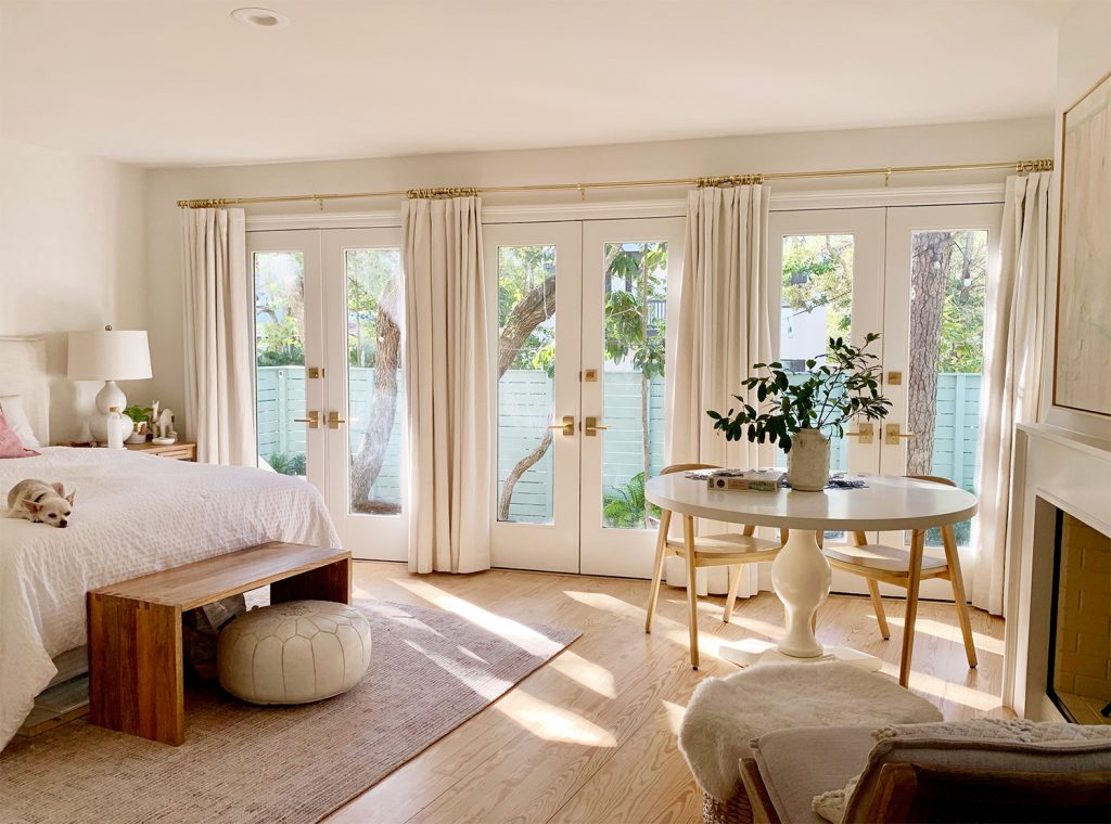 Bedroom with three french doors with with curtains and sunlight coming in