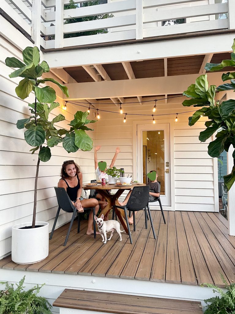 Sherry with kids and dog dining on outdoor kitchen porch with large fiddle leaf figs