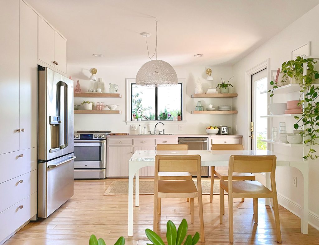 Full view of white kitchen with mauve cabinets and wood chairs