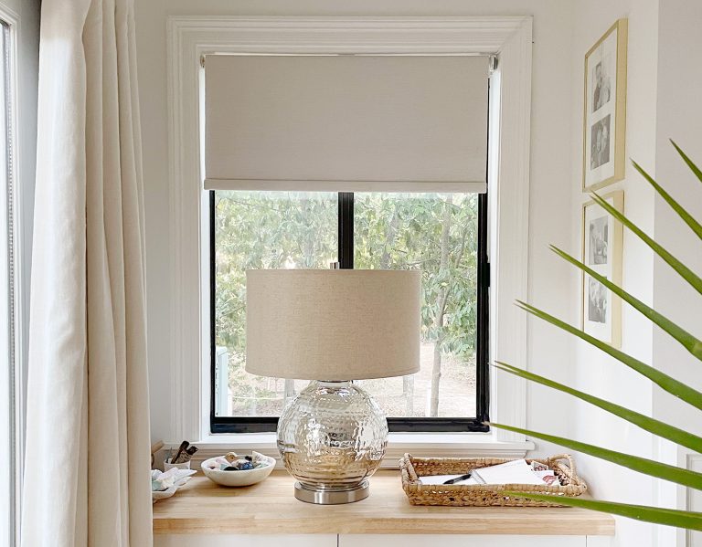 Smart roller blinds closing behind lamp in bedroom