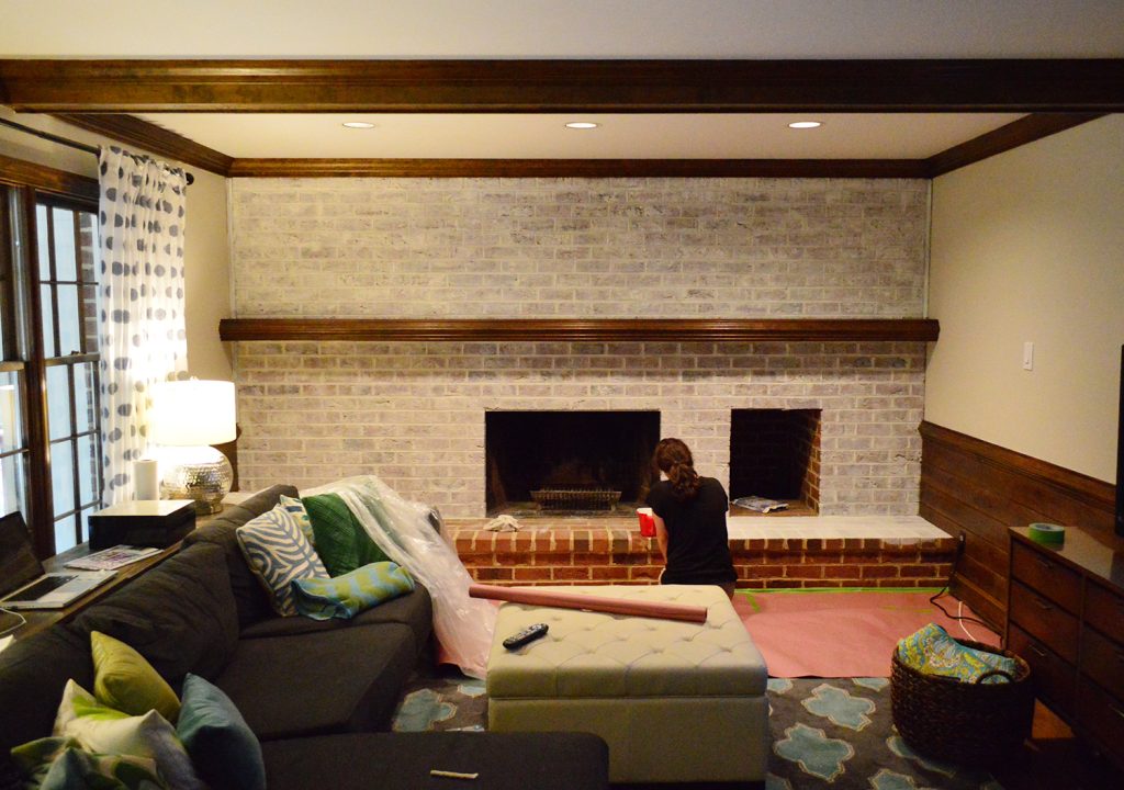 nearly completed coat of whitewash paint technique on fireplace brick wall in dated living room