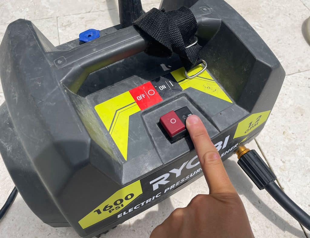 Pressing power button on Ryobi electric pressure washer