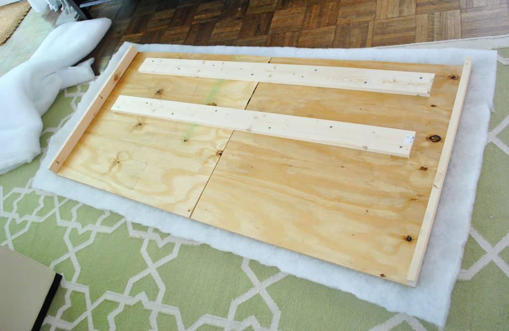Layer of batting placed under DIY headboard wood frame