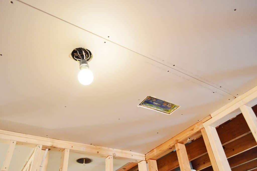 drywall hung in ceiling with hole cut for light and HVAC vent