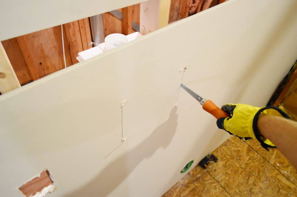 using drywall saw to cut hole for laundry plumbing in drywall sheet
