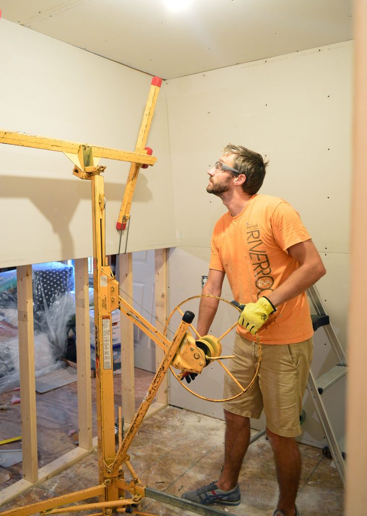 John lifting drywall panel into place on laundry room wall