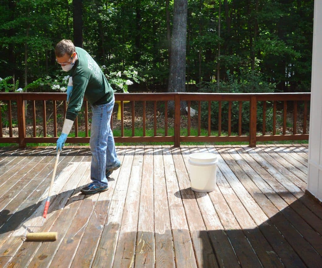 John applying deck stripper to wood deck in the sun